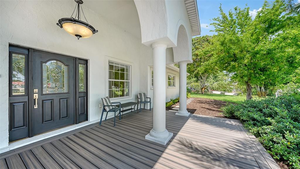 A covered porch features a dark front door, two chairs, and white columns — 2465 FOSTER LANE, SARASOTA, FL