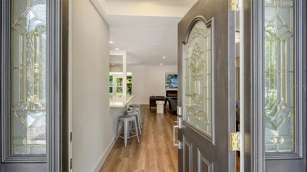 A view through an open front door into a home with wood-look flooring and stools — 2465 FOSTER LANE, SARASOTA, FL