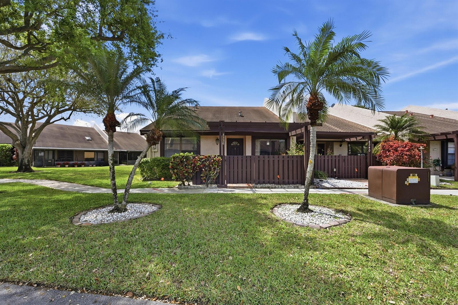 A single-story townhouse with a brown wooden fence and two palm trees in the front yard — 8336 NW 37th Place, Sunrise FL 33351, SUNRISE, FL
