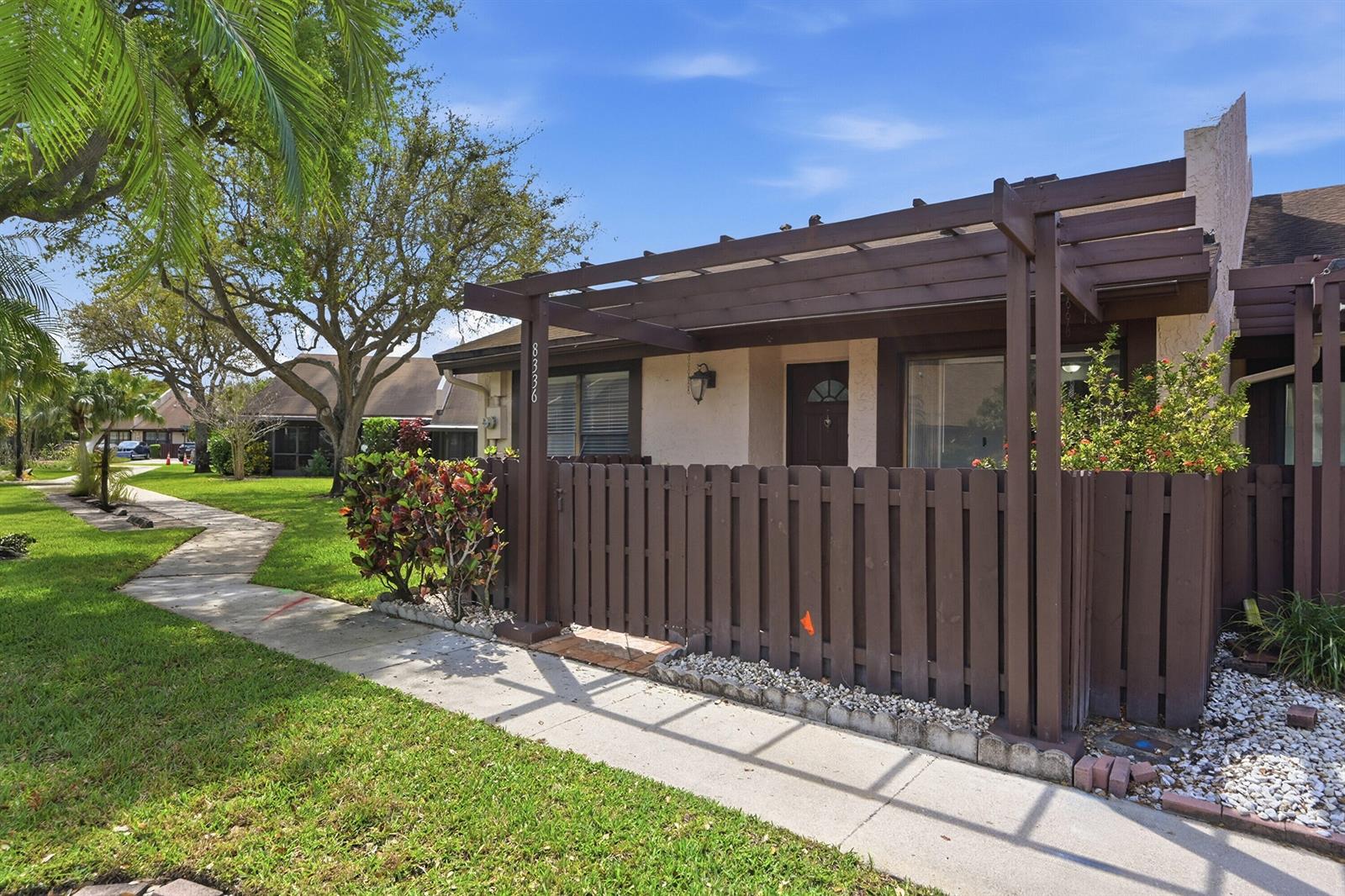 A single-story residential unit features a brown wooden pergola, a fenced courtyard, and a walkway — 8336 NW 37th Place, Sunrise FL 33351, SUNRISE, FL