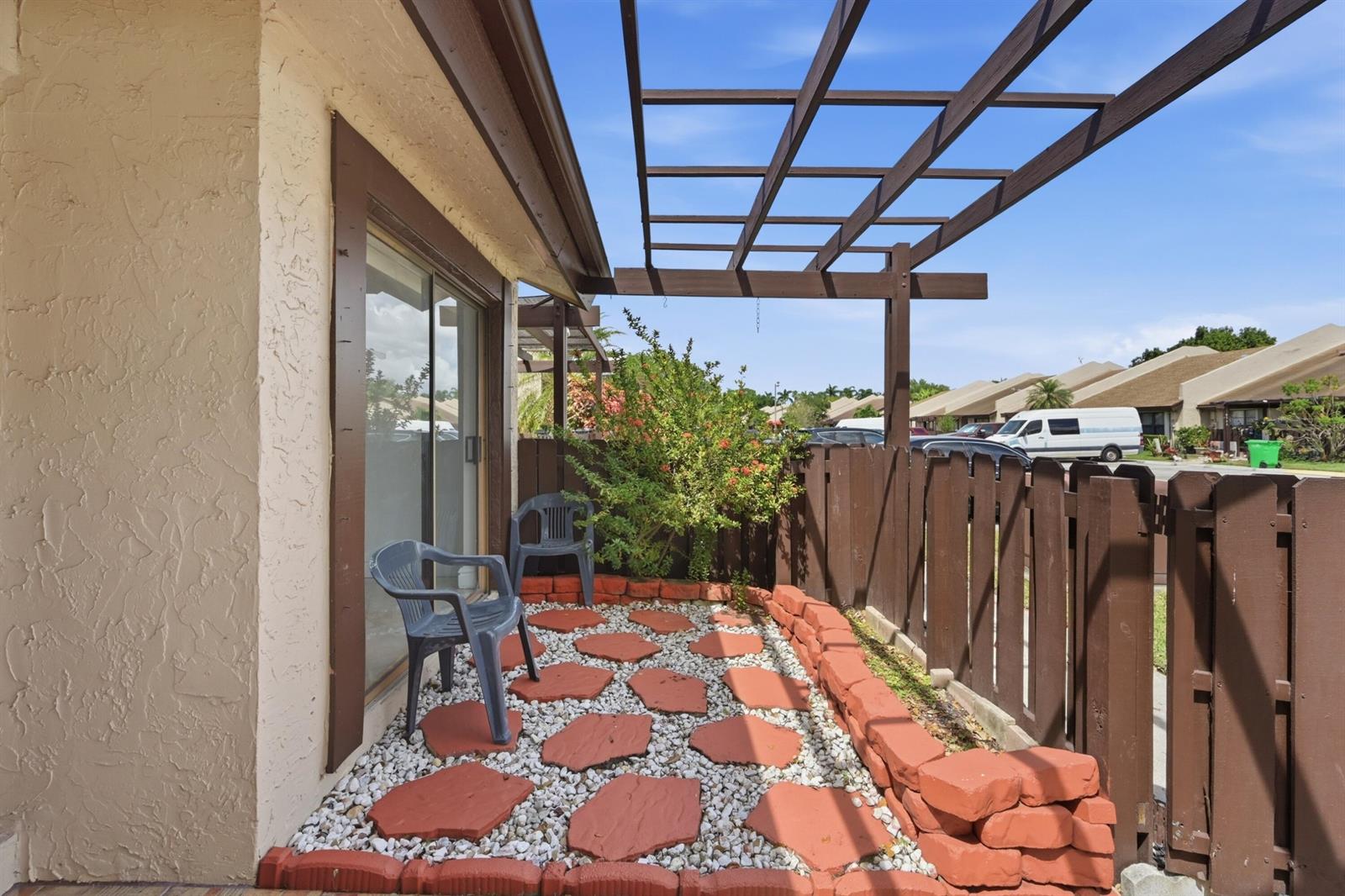 A small patio features a gravel floor with stone pavers, a wooden pergola, and fencing — 8336 NW 37th Place, Sunrise FL 33351, SUNRISE, FL