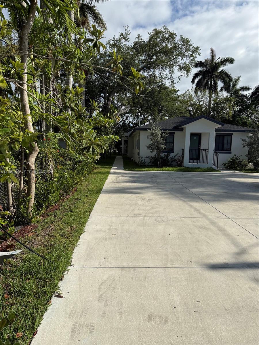 A concrete driveway leads to a single-story house with a white exterior and dark trim — 210 SW 3rd St, Florida City FL 33034, FLORIDA CITY, FL