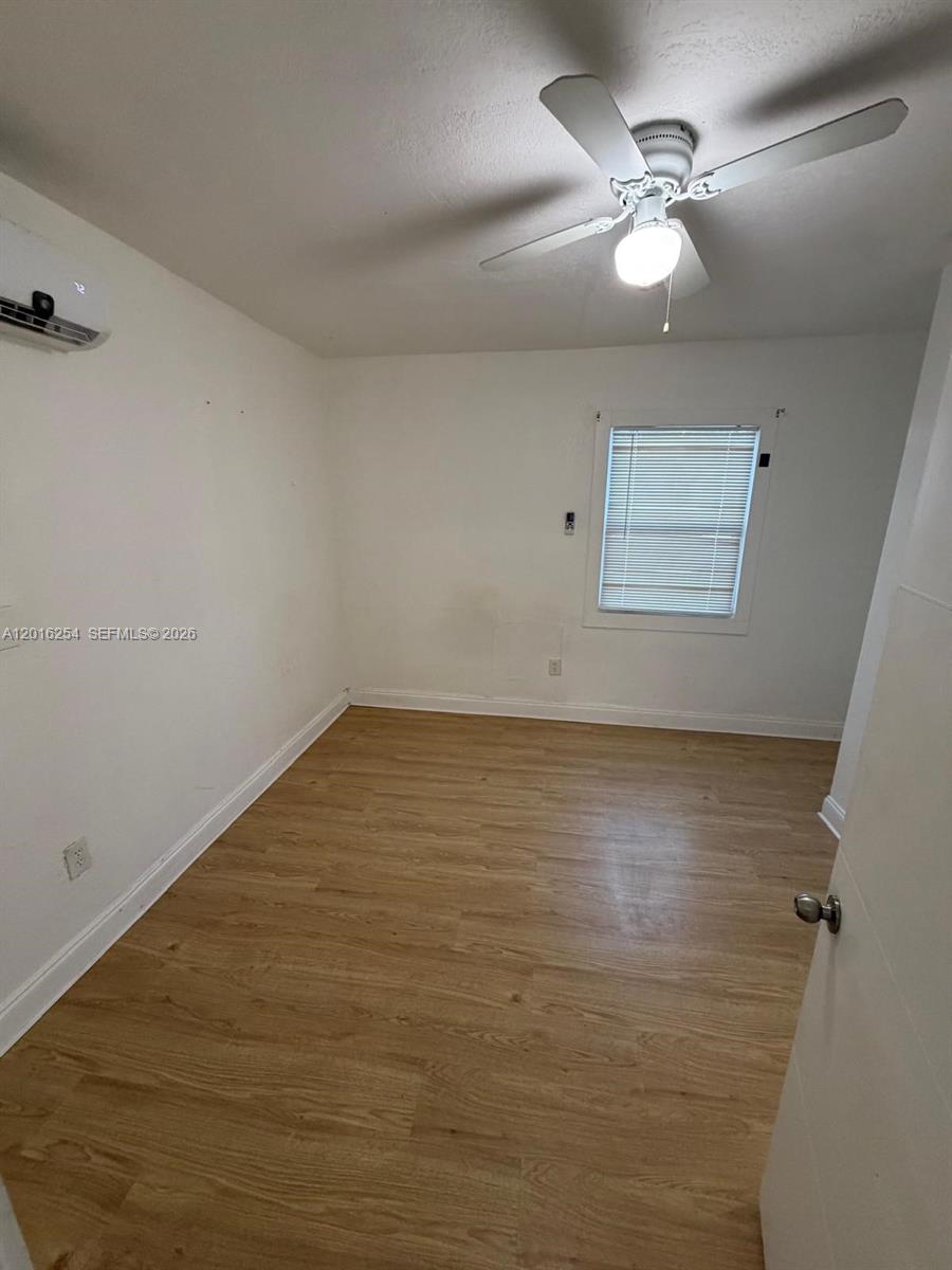 A bedroom features light wood-look flooring, a ceiling fan, and a wall-mounted air conditioner — 9050 NW 31st Ave # 2, Miami FL 33147, MIAMI, FL