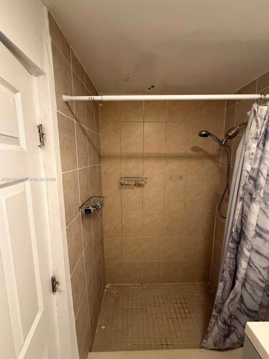 A tiled walk-in shower features a handheld showerhead, a wire caddy, and a curtain — 9050 NW 31st Ave # 2, Miami FL 33147, MIAMI, FL