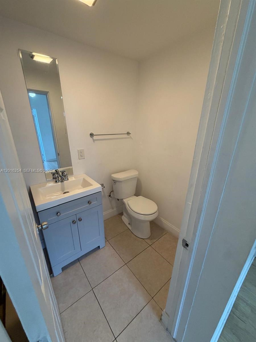 A small bathroom features a light blue vanity, a white toilet, and beige floor tiles — 9050 NW 31st Ave # 2, Miami FL 33147, MIAMI, FL
