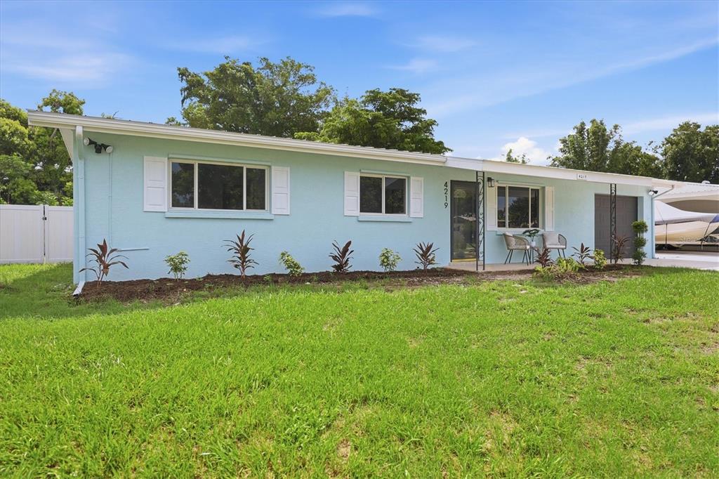 A light blue single-story house with white shutters and a front lawn — 4219 DEERFIELD DRIVE, SARASOTA, FL