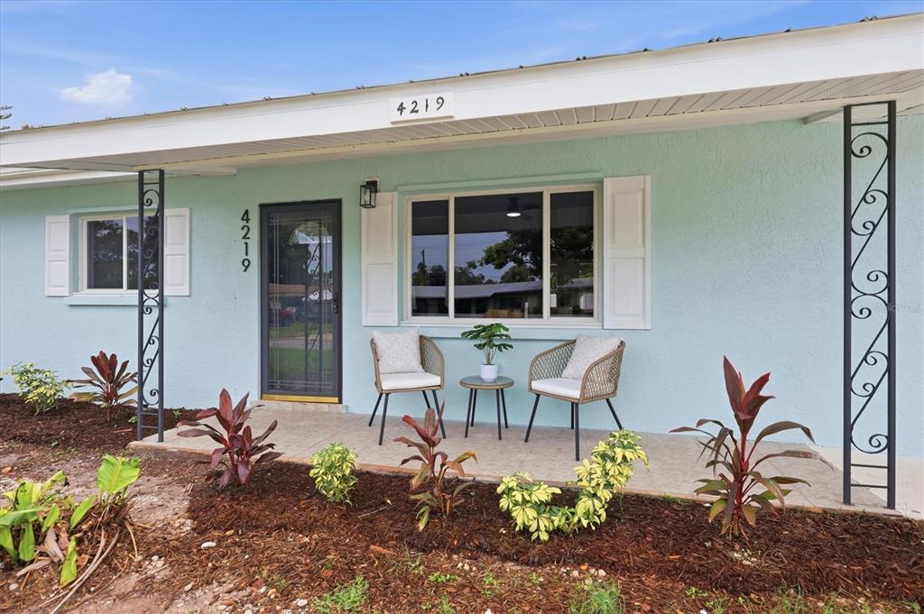 A light blue house exterior features a front porch with two chairs and a table — 4219 DEERFIELD DRIVE, SARASOTA, FL