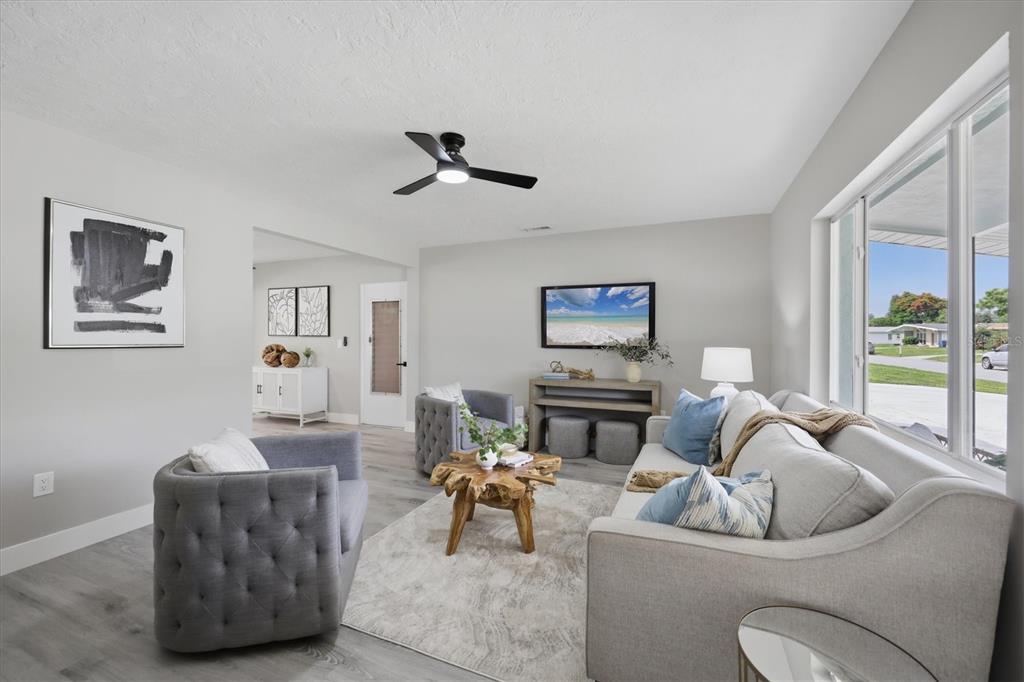 A living room features gray tufted armchairs, a light sofa, and a natural wood coffee table — 4219 DEERFIELD DRIVE, SARASOTA, FL