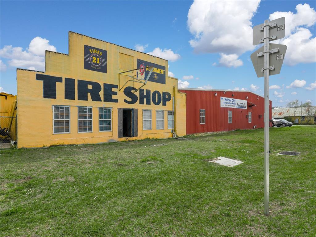 A yellow building labeled Tire Shop stands next to a red metal automotive repair shop — 301 US HIGHWAY 17 92 N, HAINES CITY, FL