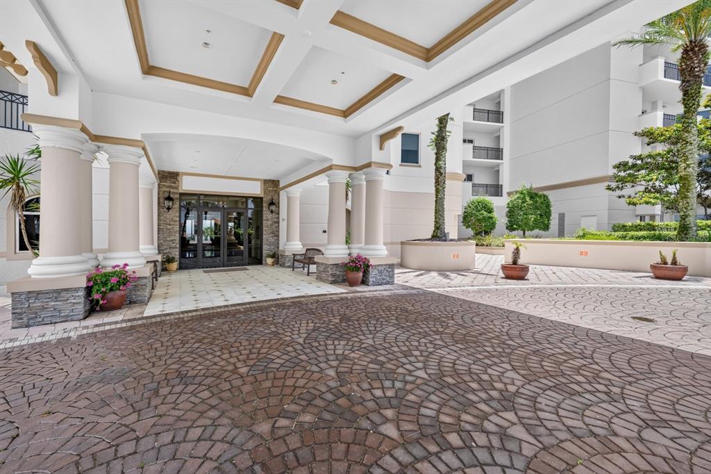 A paved driveway leads to the covered entrance of a multi-story building with stone columns — 85 AVENUE DE LA MER UNIT 502, PALM COAST, FL