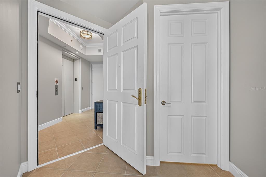 A hallway features a tiled floor, an open doorway to an elevator lobby, and a door — 85 AVENUE DE LA MER UNIT 502, PALM COAST, FL