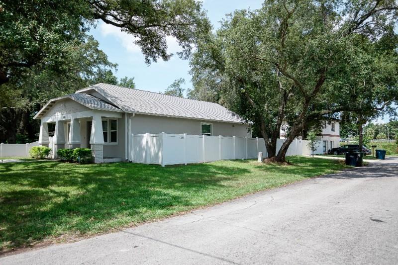 A light-colored house with a front porch and white vinyl fence sits on a lawn — 705 E ELM STREET, TAMPA, FL