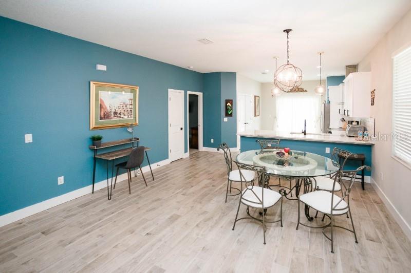 A dining area with a glass table, metal chairs, and a desk against a blue wall — 705 E ELM STREET, TAMPA, FL