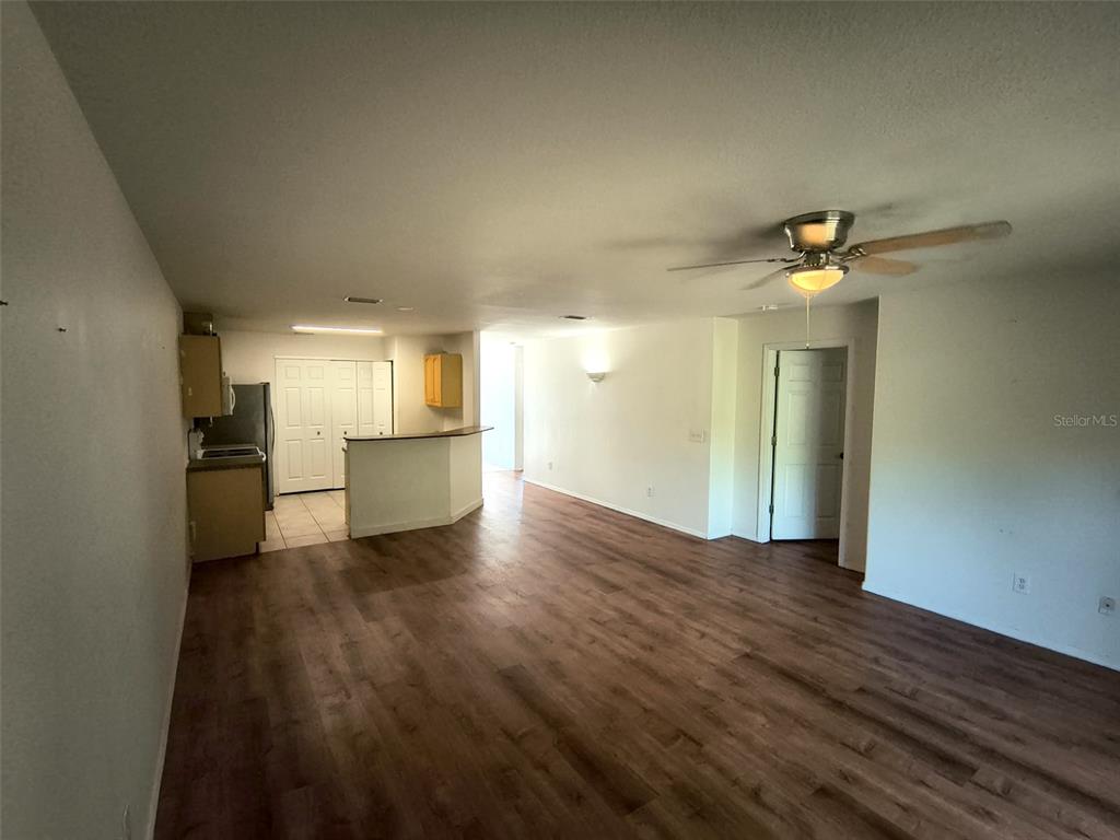 A living room with wood-look flooring leads to an open kitchen with a breakfast bar — 4 PROSPECT LANE UNIT A, PALM COAST, FL