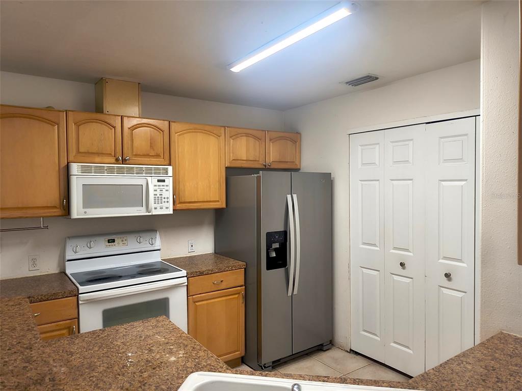 A kitchen features wood cabinets, stainless steel appliances, and brown countertops — 4 PROSPECT LANE UNIT A, PALM COAST, FL