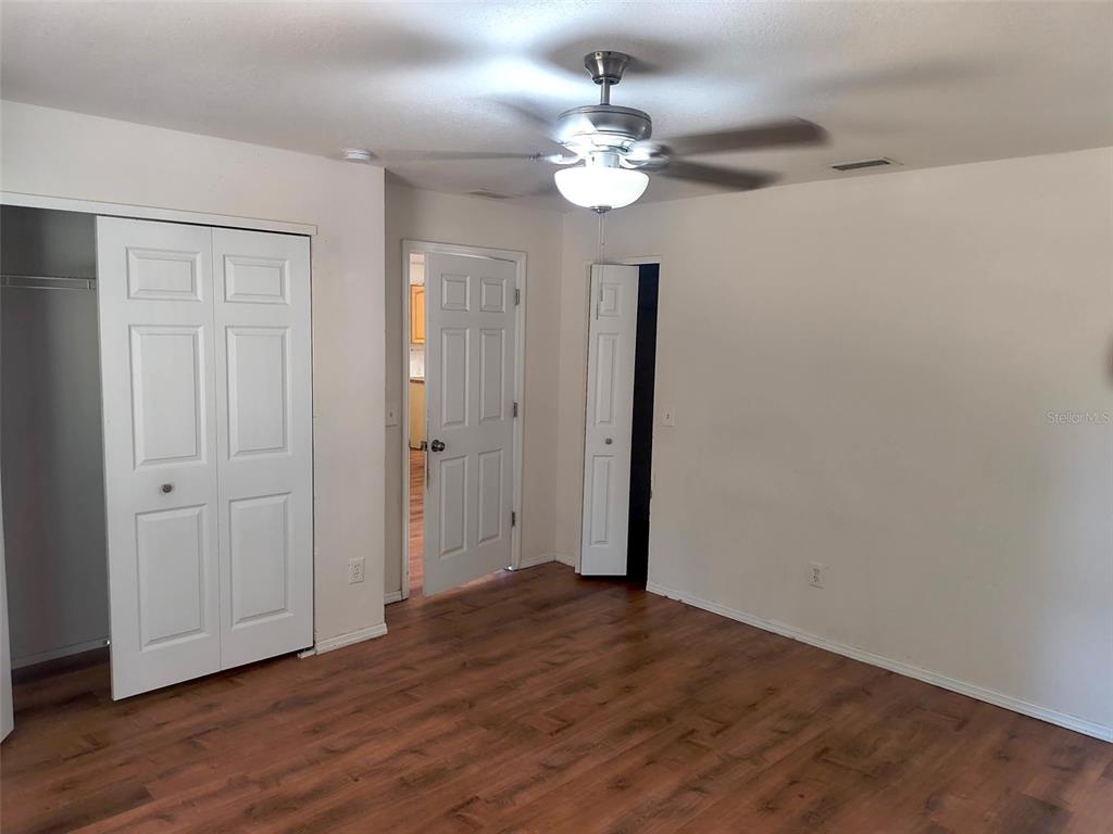 An empty room features wood-look flooring, a ceiling fan, and two sets of closet doors — 4 PROSPECT LANE UNIT A, PALM COAST, FL