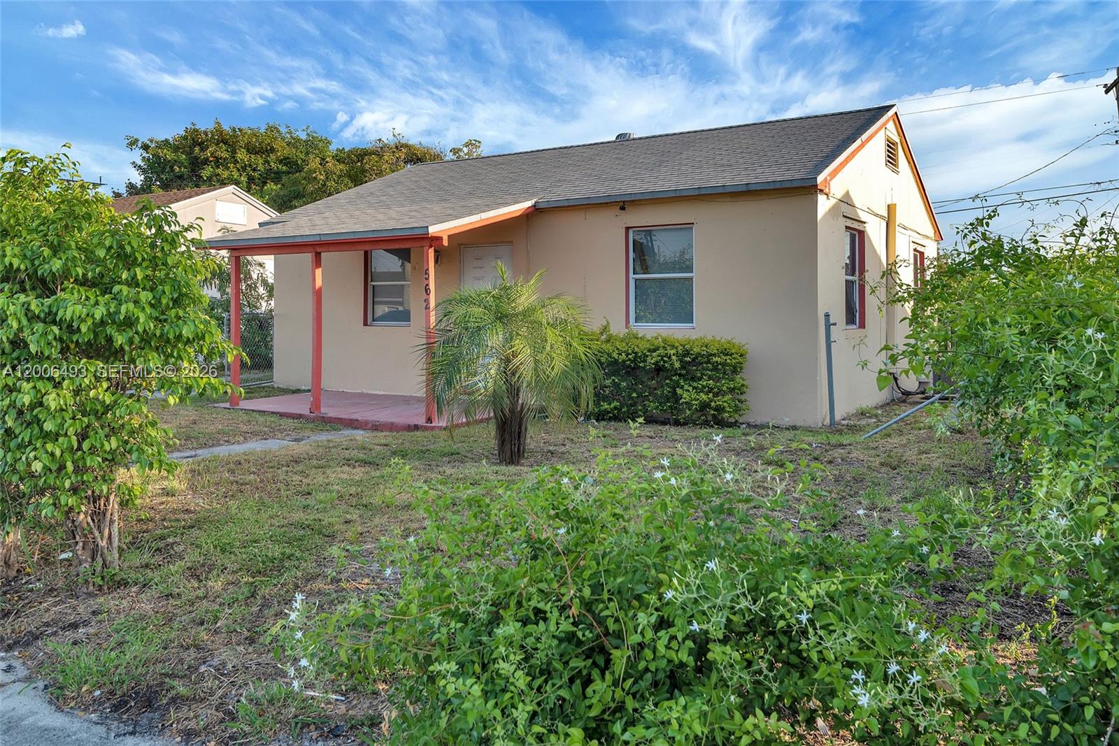 A single-story house with a covered porch, tan stucco walls, and a shingled roof — 562 W 4th St, Riviera Beach FL 33404, RIVIERA BEACH, FL