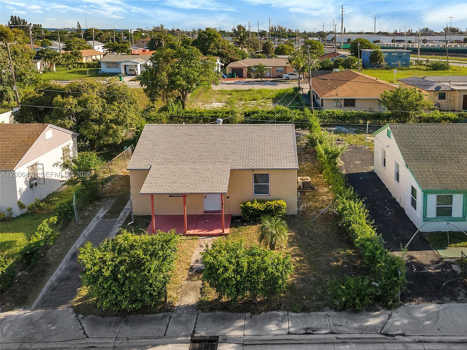 An aerial view shows a single-story house with a tan exterior and a front porch — 562 W 4th St, Riviera Beach FL 33404, RIVIERA BEACH, FL