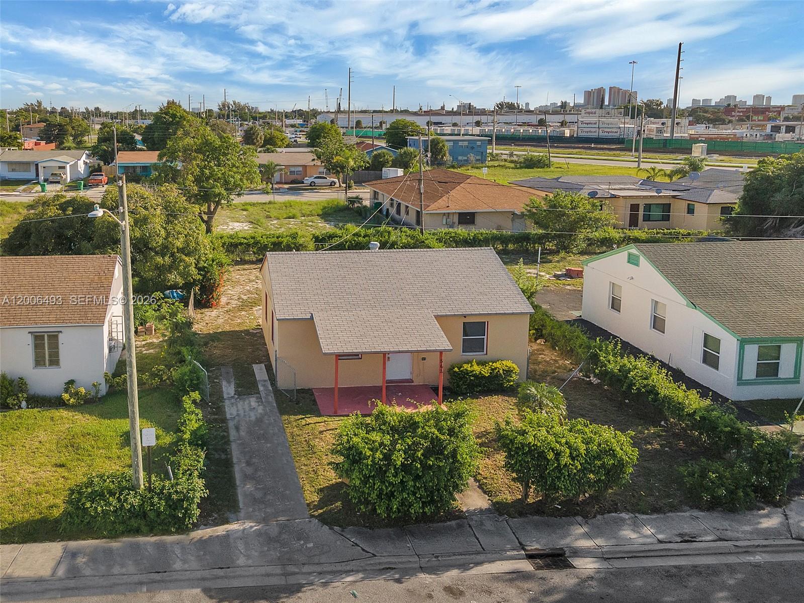 An aerial view shows a single-story tan house with a porch and a concrete driveway — 562 W 4th St, Riviera Beach FL 33404, RIVIERA BEACH, FL