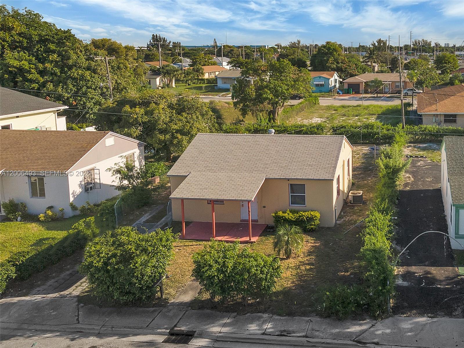 An aerial view shows a single-story house with a tan exterior and a covered porch — 562 W 4th St, Riviera Beach FL 33404, RIVIERA BEACH, FL