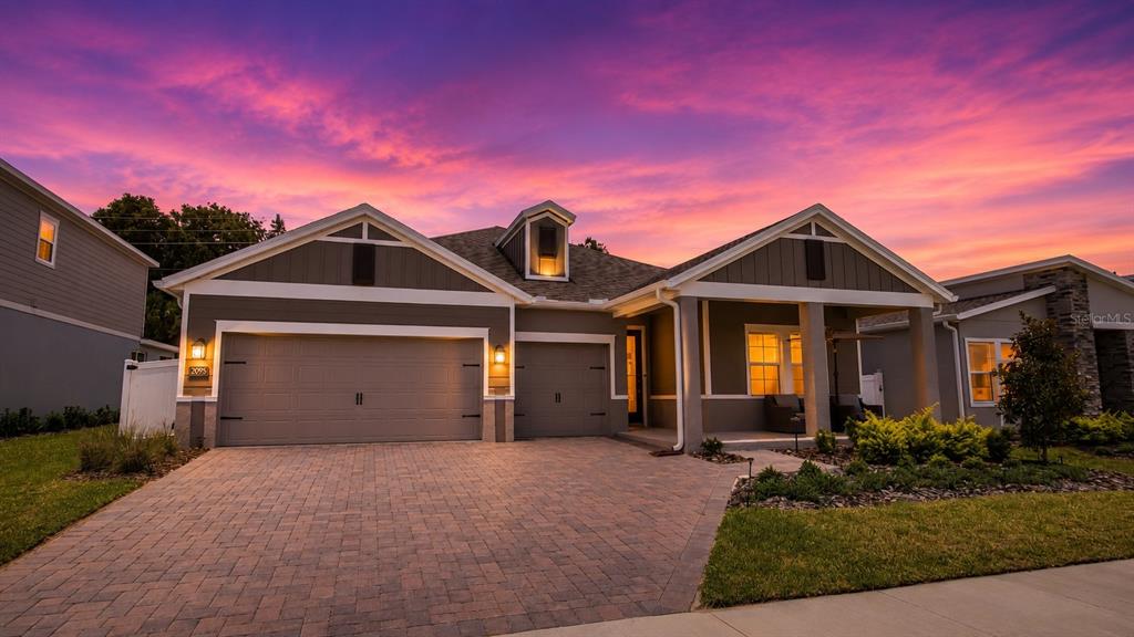 A single-story house with a two-car garage and a paved driveway at sunset — 2095 RIDER RAIN LANE, APOPKA, FL