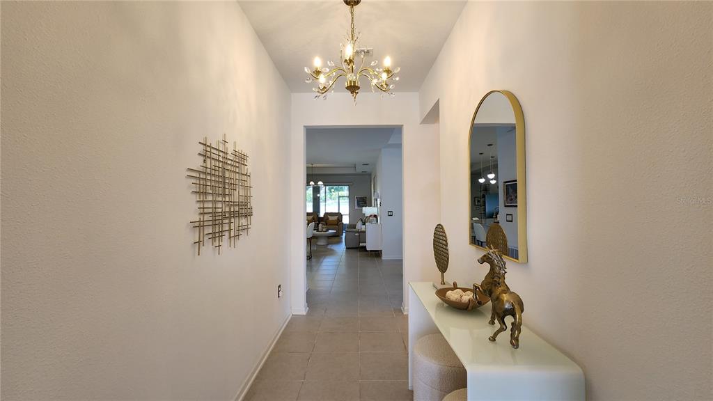 A foyer features a chandelier, a console table with a horse statue, and wall art — 2095 RIDER RAIN LANE, APOPKA, FL