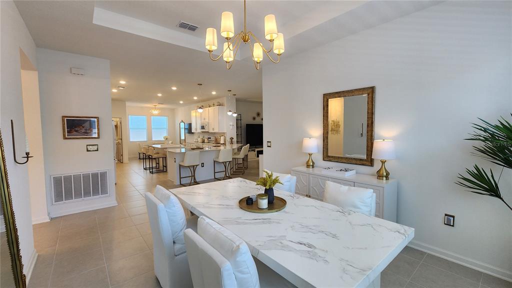 A dining area with a marble table and chandelier opens into a white kitchen — 2095 RIDER RAIN LANE, APOPKA, FL