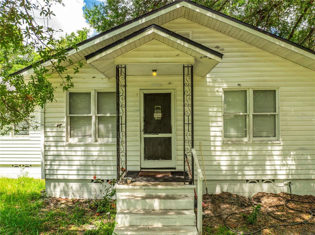 A white, single-story house with a front porch, screen door, and concrete steps — 2536 MAGNOLIA AVENUE, SANFORD, FL