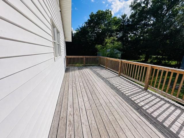A wooden deck extends along the side of a house with white horizontal siding — 2536 MAGNOLIA AVENUE, SANFORD, FL