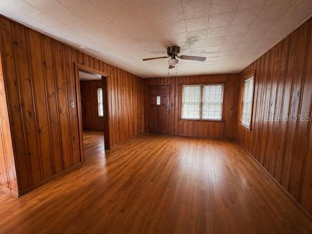 A living room features wood-paneled walls, hardwood flooring, a ceiling fan, and a front door — 2536 MAGNOLIA AVENUE, SANFORD, FL