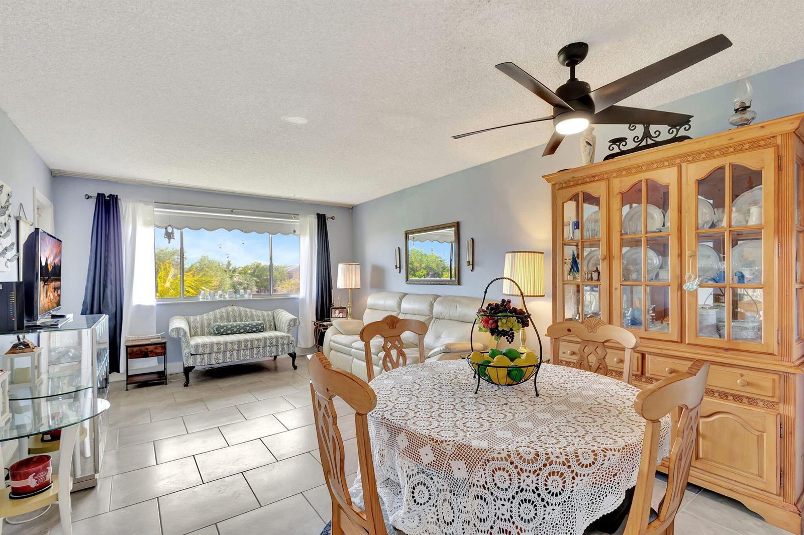 A dining and living area features a round table, china cabinet, sofa, and tile flooring — 2812 Garden Drive S # 308, FL 33461, FL
