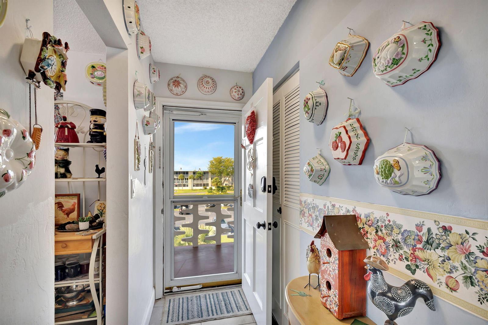 An entryway features walls decorated with ceramic molds, a birdhouse, and a door to a balcony — 2812 Garden Drive S # 308, FL 33461, FL