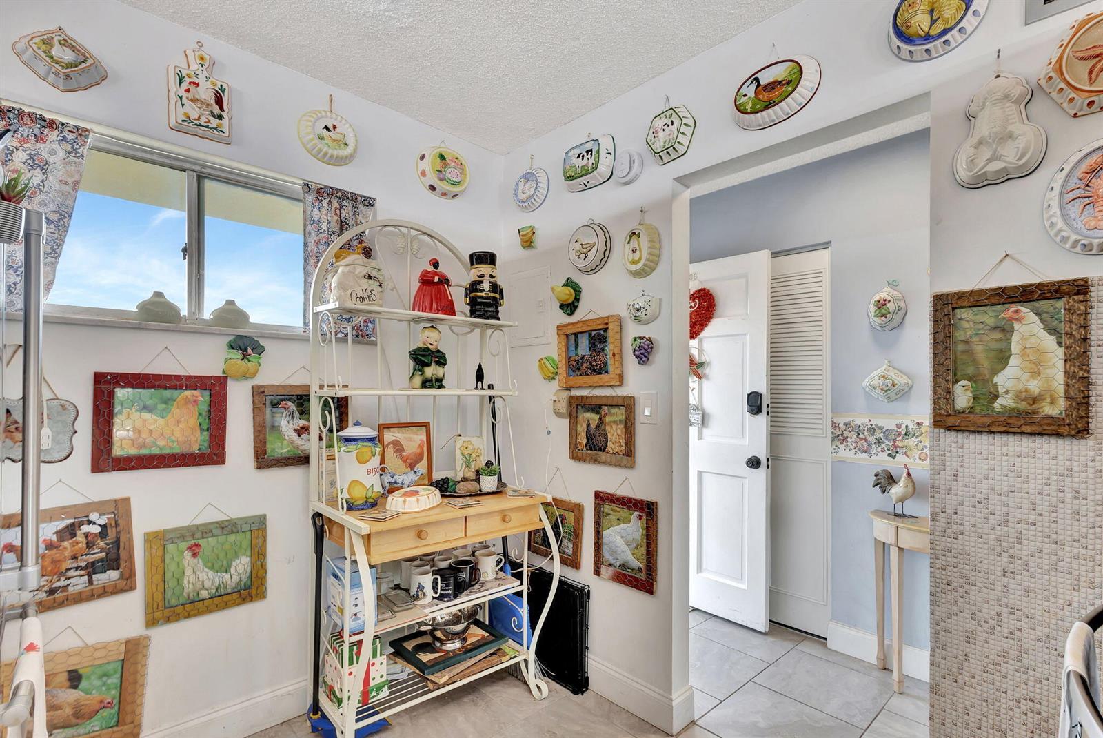 A kitchen wall is decorated with numerous chicken-themed pictures, plates, and molds — 2812 Garden Drive S # 308, FL 33461, FL