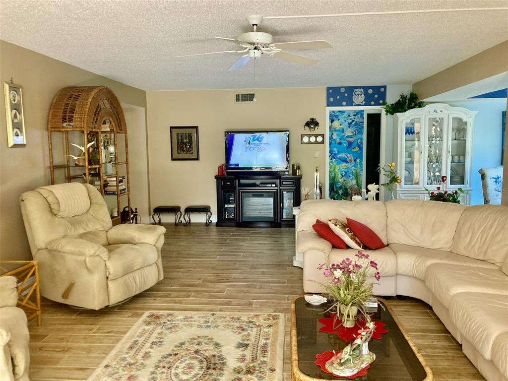 A living room features a beige sectional, a recliner, a television console, and tile flooring — 6002 OAK CREEK LANE UNIT 1925, BRADENTON, FL