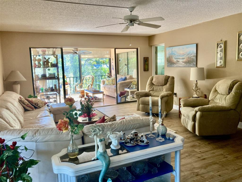 A living room features a white sofa, two beige recliners, and a sliding glass door — 6002 OAK CREEK LANE UNIT 1925, BRADENTON, FL