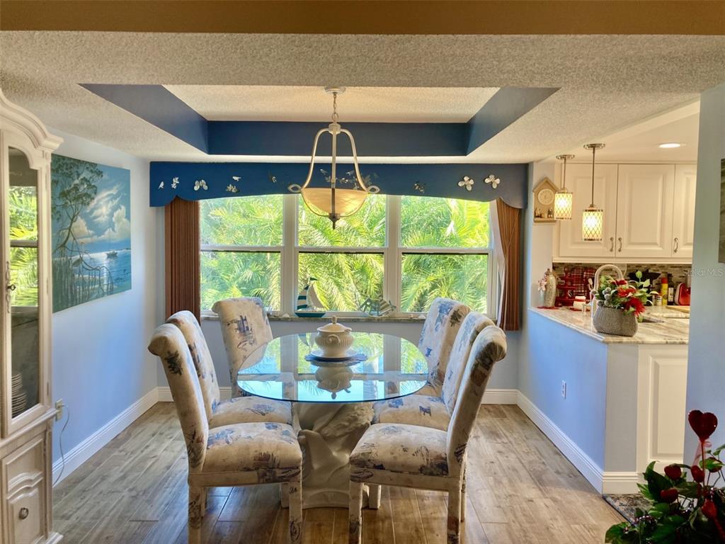 A dining area features a glass-topped table, upholstered chairs, blue walls, and a tray ceiling — 6002 OAK CREEK LANE UNIT 1925, BRADENTON, FL