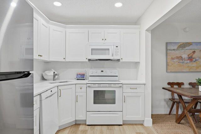 A kitchen with white cabinets, stainless steel appliances, and a dining area to the right — 3561 Tall Pine Way # C2, FL 33463, FL