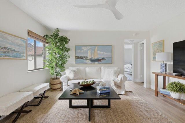 A living room features a white sofa, a dark coffee table, and a large potted plant — 3561 Tall Pine Way # C2, FL 33463, FL
