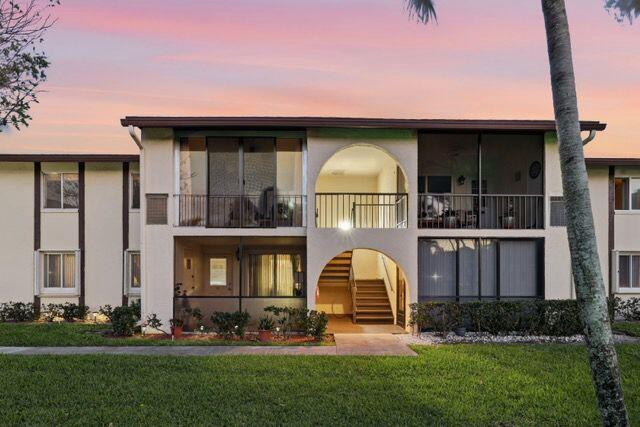 A two-story apartment building features arched entryways, screened balconies, and a landscaped lawn — 3561 Tall Pine Way # C2, FL 33463, FL