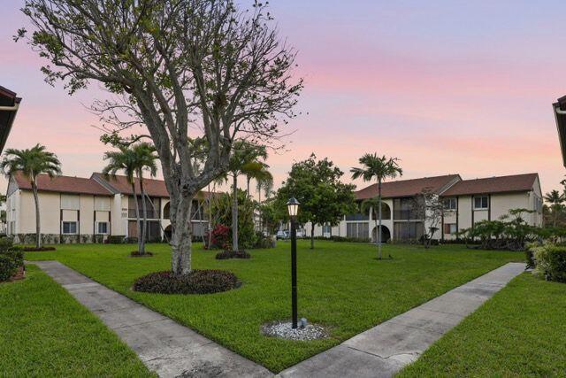 A grassy courtyard sits between two-story apartment buildings with palm trees and a lamp post — 3561 Tall Pine Way # C2, FL 33463, FL