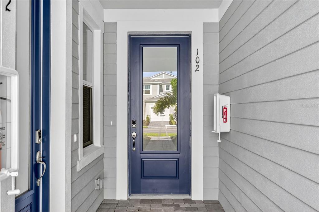 A blue front door with a glass panel is set in a gray-sided entryway — 17420 MOONFLOWER DRIVE UNIT 102, VENICE, FL