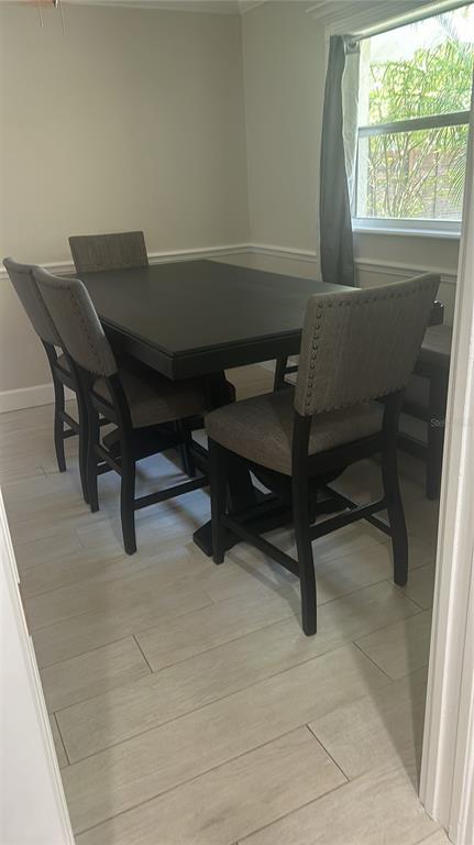 A dining room features a dark wood table with upholstered chairs on light tile flooring — 7641 VILLAGE GREEN DRIVE, WINTER PARK, FL