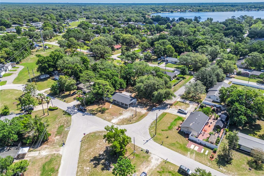 An aerial view shows a residential neighborhood with houses, trees, and a nearby lake — 2201 CAMELLIA DRIVE, LONGWOOD, FL