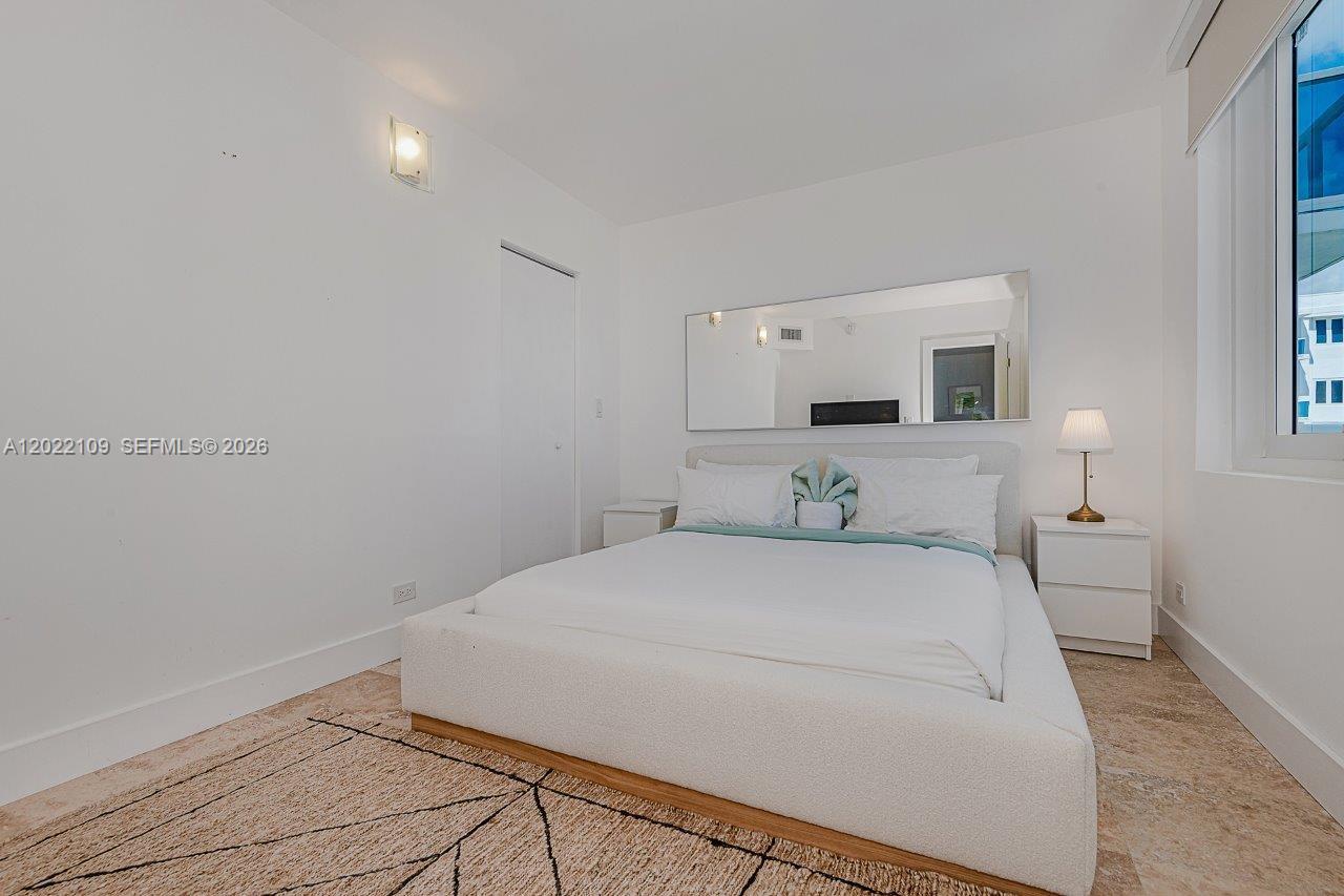 A bedroom features a white platform bed, a large wall mirror, and a window — 2301 Collins Ave # 1515, Miami Beach FL 33139, MIAMI BEACH, FL