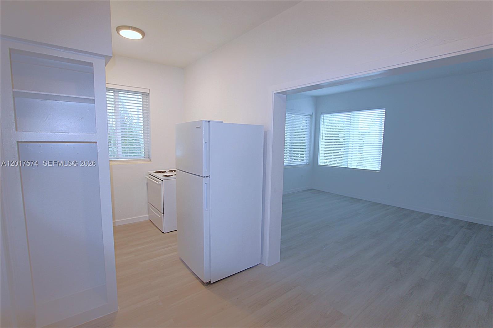 A kitchen with a white refrigerator and stove connects to an adjacent living area — 1115 Euclid Ave # 17, Miami Beach FL 33139, MIAMI BEACH, FL