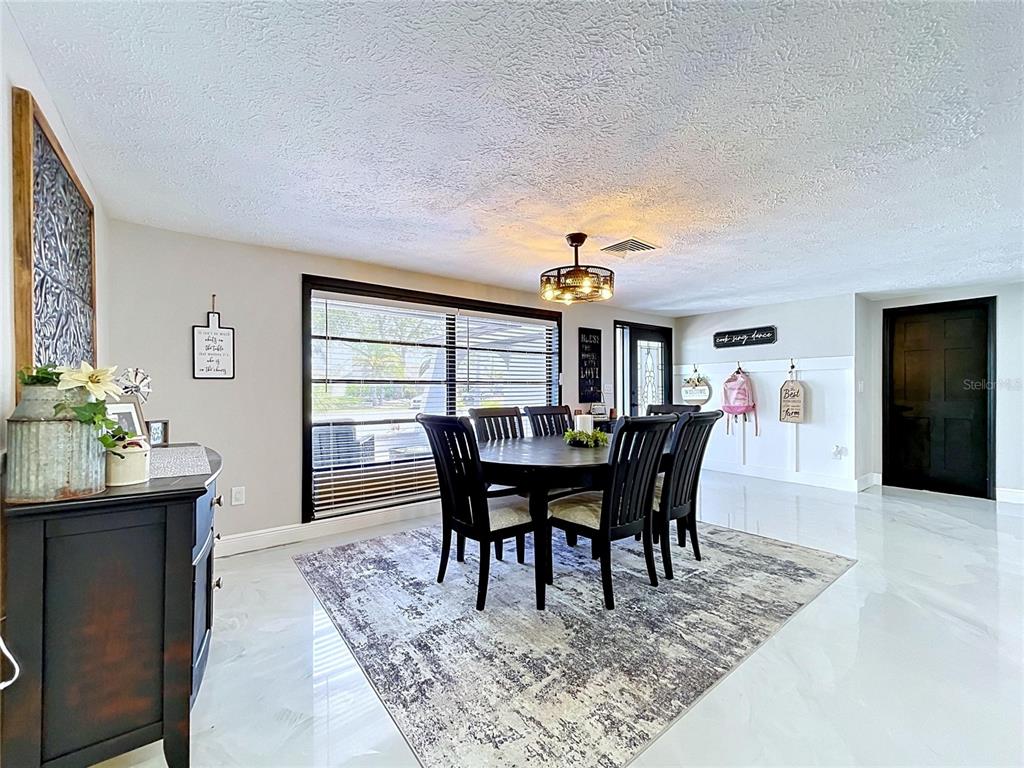 A dining room features a dark wood table, black chairs, and a patterned area rug — 6950 SOUTHWIND DRIVE, HUDSON, FL