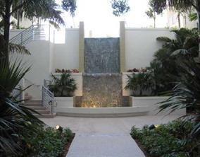 A tiered stone waterfall feature sits between two white walls with stairs and tropical landscaping — 1830 Radius Drive # 225, Hollywood FL 33020, HOLLYWOOD, FL
