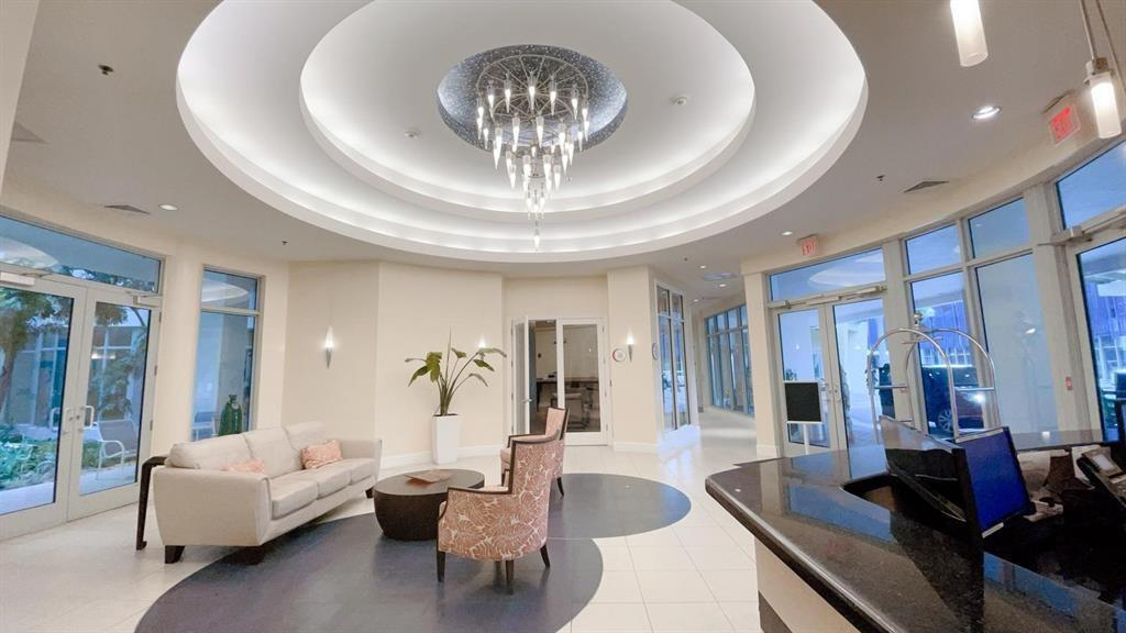 A bright hotel lobby features a circular tray ceiling, a modern chandelier, and seating areas — 1830 Radius Drive # 225, Hollywood FL 33020, HOLLYWOOD, FL