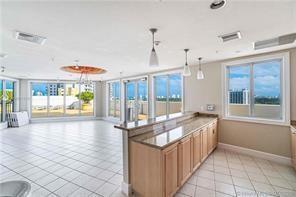 A bright, tiled room features a kitchen island with wooden cabinets and large glass windows — 1830 Radius Drive # 225, Hollywood FL 33020, HOLLYWOOD, FL