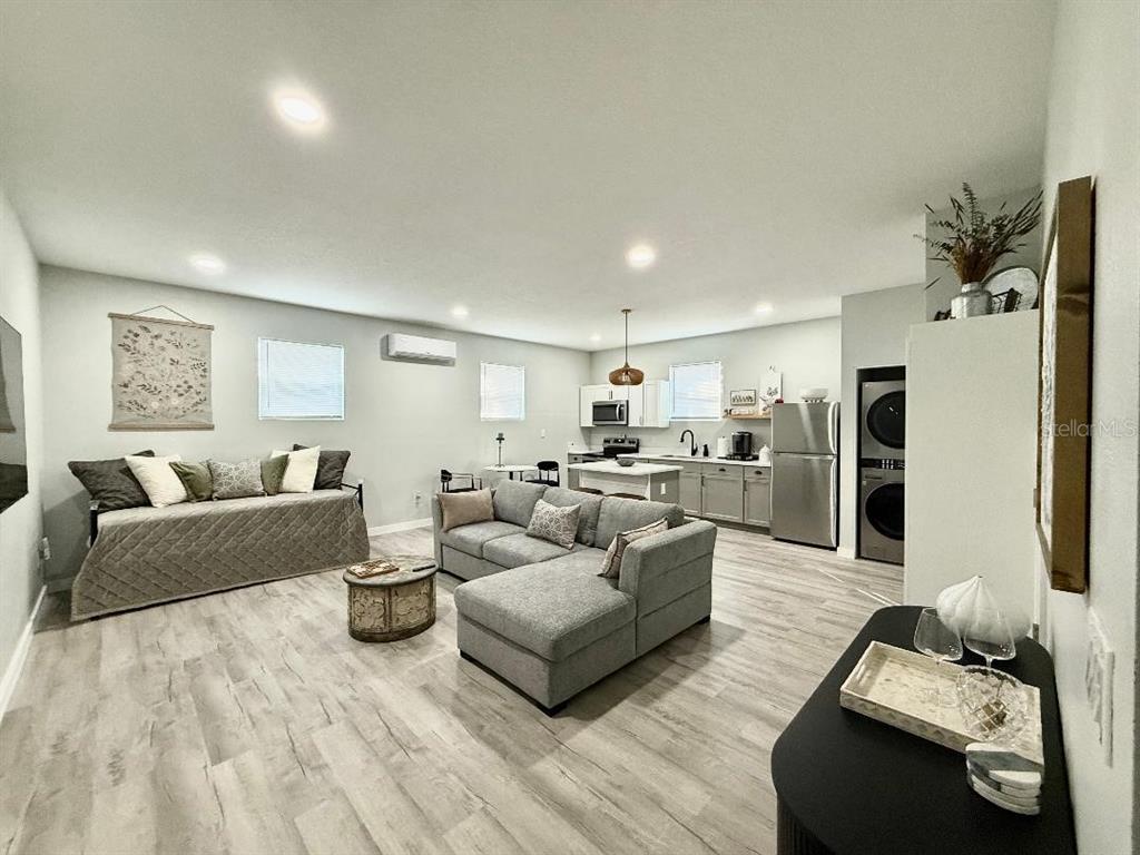 An open-concept living room and kitchen area with gray flooring and neutral furniture — 1183 CHESTNUT STREET UNIT B, CLERMONT, FL